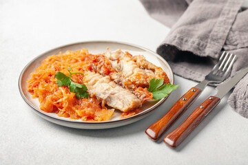Fish pollock fillet with garnish stewed cabbage in a plate on the table. Healthy diet