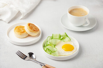 Eggs, cucumber in a plate and curd pancakes on the table.  Healthy breakfast