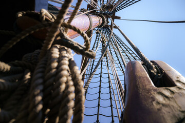 Mast and rigging of old wooden VOC sailing ship with ropes, rope loaders and pulleys
