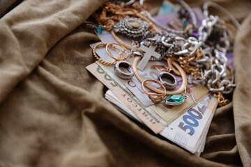 Bunch of stolen jewelry and money on military uniform cloth fabric. Looting by Russian soldiers in...