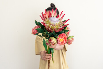 A young woman with protea flower on a white background. - obrazy, fototapety, plakaty