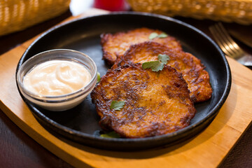 Fried grated potato pancakes with sour cream on frying pan