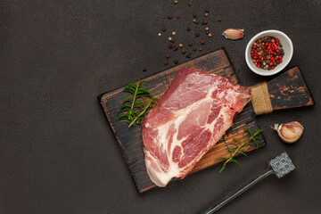Fototapeta na wymiar Raw beef steak with spices on a dark board. Top view