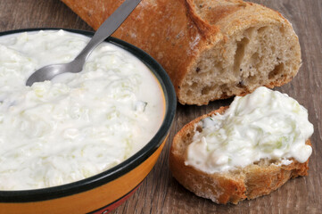 Ramequin de tzatzíki maison posés avec du pain et une tartine de tzatzíki en gros plan