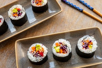 Vegan Futomaki (thick sushi rolls) with zucchini, celery stalks, carrot, red cabbage, red bell pepper and wasabi sprinkled with sesame seeds.