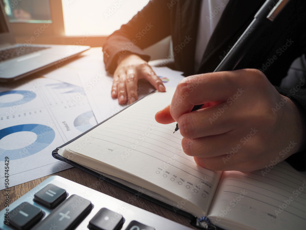 Poster businessman analyzing charts and taking detailed notes through a notebook, attending an online telec