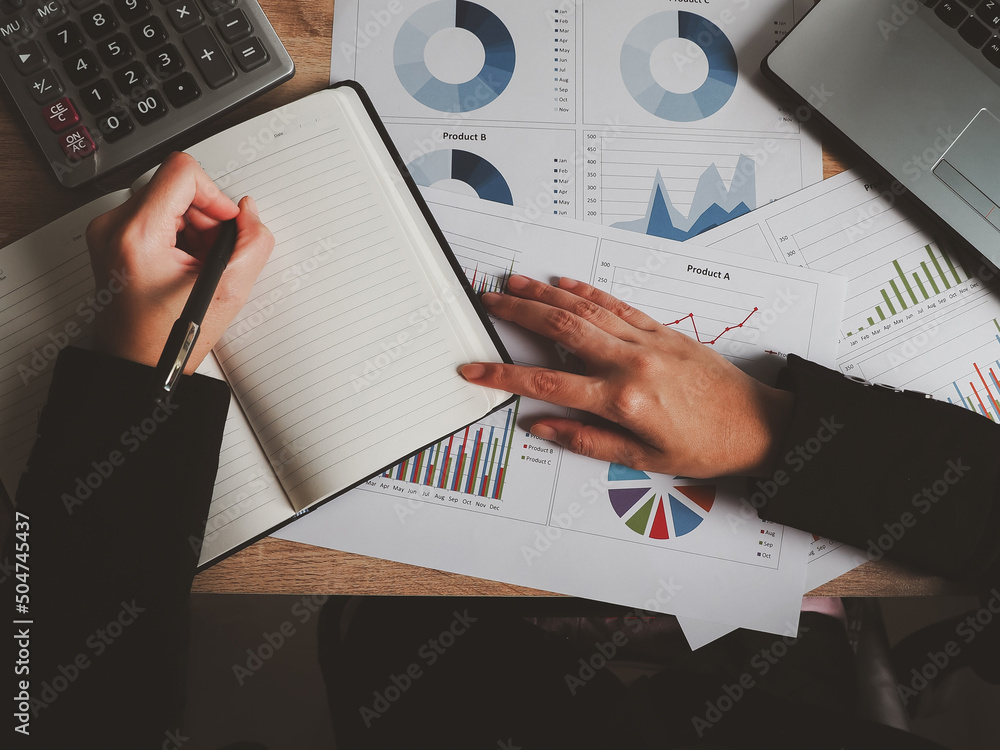 Poster businessman analyzing charts and taking detailed notes through a notebook, attending an online telec