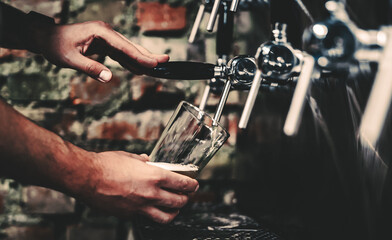 Fototapeta na wymiar bartender hand at beer tap pouring a draught beer in glass serving in a bar or pub. tap room