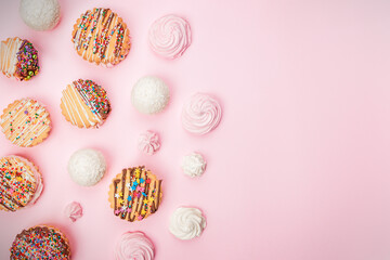 Cakes cookies sandwiches decorated with chocolate and multicolored stars and handmade marshmallows lie on a pink background.