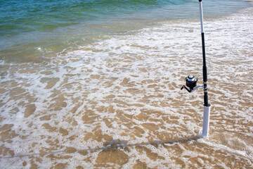 shoreline ocean sea fishing pole with plastic cylinder fishing pole mount holder spiked in sand