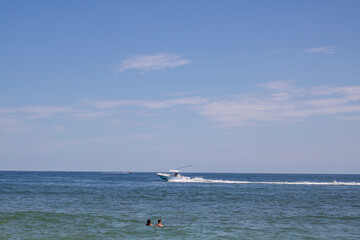 A couple in the water watching a motor boat go by in ocean waters