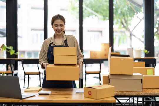 Startup SME small business entrepreneur SME or freelance Asian woman using a laptop with box, online marketing packaging box and delivery, SME concept