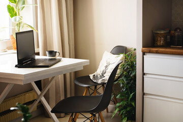 Home work place on kithcen, table with laptop, chair, plant,