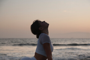 Healthy with Yoga Concept. Urdhva Mukha Shvanasana. Attractive young woman practice Cobra Pose on the beach during sunset. Comfortable and relax.