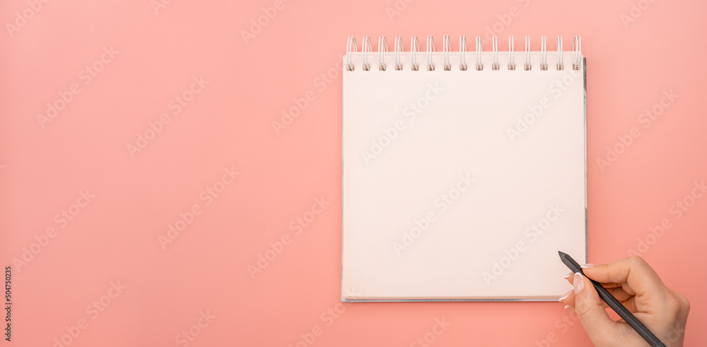 Aufkleber mockup notepad. writing in blank notepad on pink background. woman hand with pen next to an empty bl