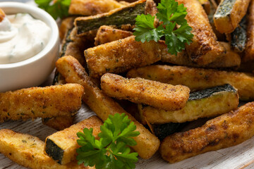 Crispy zucchini fries with sauce in white wooden board