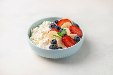 Healthy breakfast - cottage cheese with banana and berries in a bowl on the table.