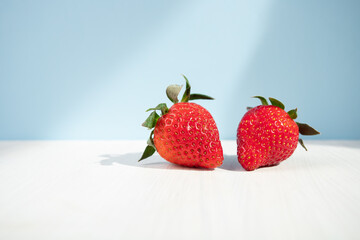 ripe red strawberries on a blue background, juicy berry in sunlight,copy space