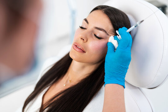 Beautician is contouring the woman's cheekbones with hyaluronic acid filler. Hyaluronic acid filler is injected by needle or cannula. Face contouring concept.