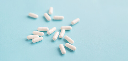 White capsule pills on a blue background. Medical background with copy space for text.	