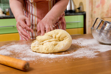 Woman kneading flour in the kitchen at home, hands and dough close-up