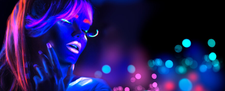 Neon Woman dancing. Fashion model girl in neon light, portrait of beautiful model with fluorescent make-up, Night club. Disco dancer posing in UV, colorful make up. On bright background