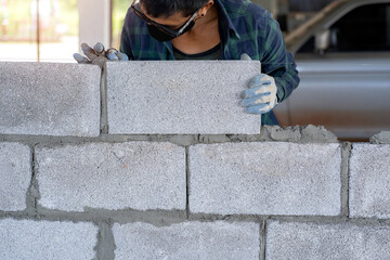 masonry worker make concrete wall by cement block and plaster at construction site