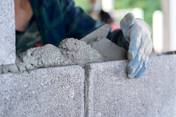 masonry worker make concrete wall by cement block and plaster at construction site
