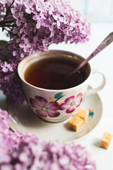 Cup of tea and flowers of a lilac on a white wooden background