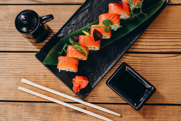 There is a beautiful decorated plate of sushi on the wooden table.
