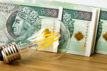 light bulb and Polish money, banknotes PLN 100 each, The concept of energy and electricity prices...