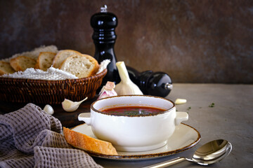 Beetroot soup with herbs and garlic against the background of the old wall.