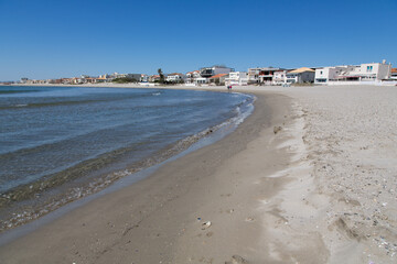 Beach landscape France: Beautiful clean non-polluted and clear water at the sandy beach of Carnon-Plage near Montpellier with its waterside vacation rentals and summer residences in the background