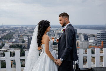 City view. High skyscrapers and a bridge across the river. Business center. Stylish wedding couple on the roof of the house. Beautiful view