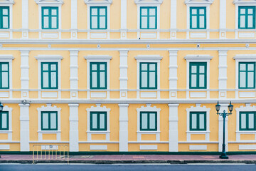 Fototapeta na wymiar Yellow building with green window in vintage style on day with clear sky