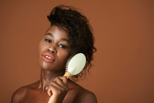 Studio Portrait Of Young Black Woman Brushing Hair After Morning Shower