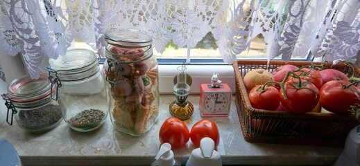 Kitchen plot on the windowsill of the kitchen there are glass jars of tea, a basket of apples and tomatoes, at red o'clock three o'clock in the afternoon, a small oil lamp is on the windowsill