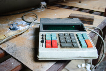 Old calculator covered in dirt on a dirty shelf