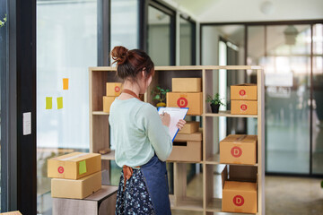 A portrait of a small startup, an SME owner, an Asian female entrepreneur checking orders to...