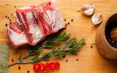 Raw pork ribs, garlic, pepper, bay leaf, on a wooden background. Raw pork rib chops on cut board...