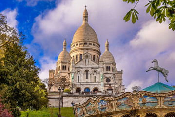 Purple cloudy twilight above the Sacré-Coeur Basilica on the top of the Montmartre hill with a carousel in the bottom right corner