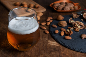 Glass with beer next to some nuts, almonds and walnuts. Close-up.