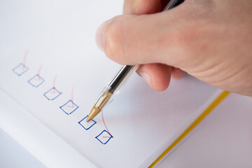 Close-up of a person's hand marking checklist