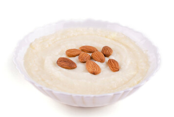 Semolina porridge with whole almonds in a beautiful bowl (plate) on a white isolated background. Space for text.