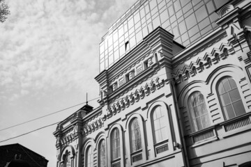 an old house against the background of a modern glass multi-storey building.