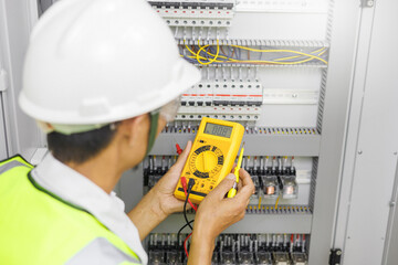 Electrical engineer or repairman holding digital multimeter and looking at the screen to inspecting...