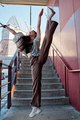 teenage woman lifting her leg above her head on city stairs