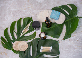 Nachhaltige Kosmetik mit Braunglasflasche, Seife, Creme, Tiegel, Abschminkpads und Q-tips aus Bambus Flatlay Gesichtspflege, exotisch inszeniert