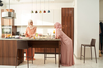 Muslim women cooking and chatting in modern kitchen