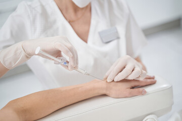 Woman receiving rejuvenation arm injection in beauty clinic